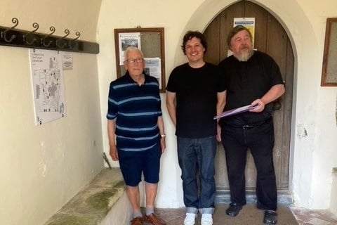 David Glennerster, Chair of Penally History Group, Tom Morgan, Flock of Clouds, the designer of the map and Father Paul Boyle, Vicar of Penally with the map on the wall and the A to Z index.