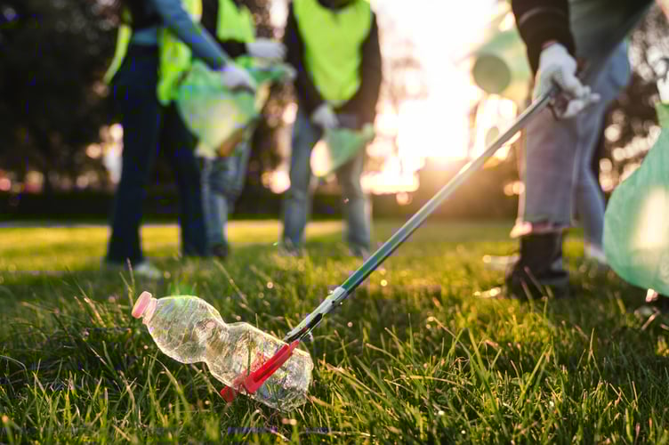 Group of adolescent volunteers cleaning together a public park. They are picking up garbage.