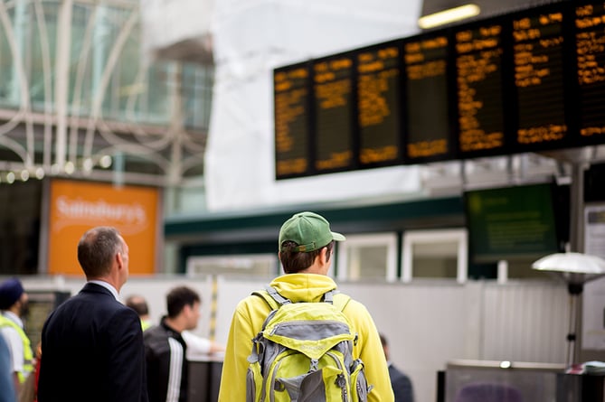 Rail passengers at station looking at timetable screens
