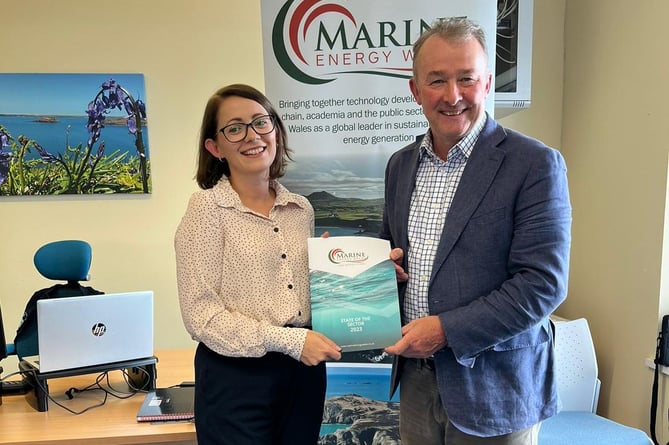 Simon Hart receives the Marine Energy Wales State of the Sector report from Communications Coordinator Jess Hill.