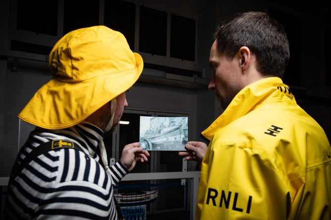 Craig Davis (ALB Crew) and William Horton (Station Mechanic) examine an old photograph of Tenby Lifeboat