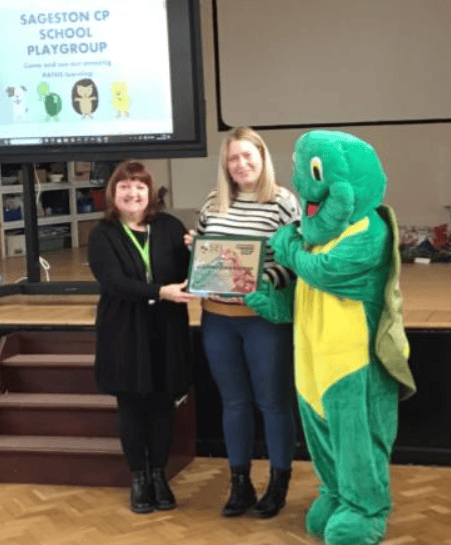 Mrs O’Leary receiving the Model Pre-School Award from Claire Sell and Twiggle from PATHS