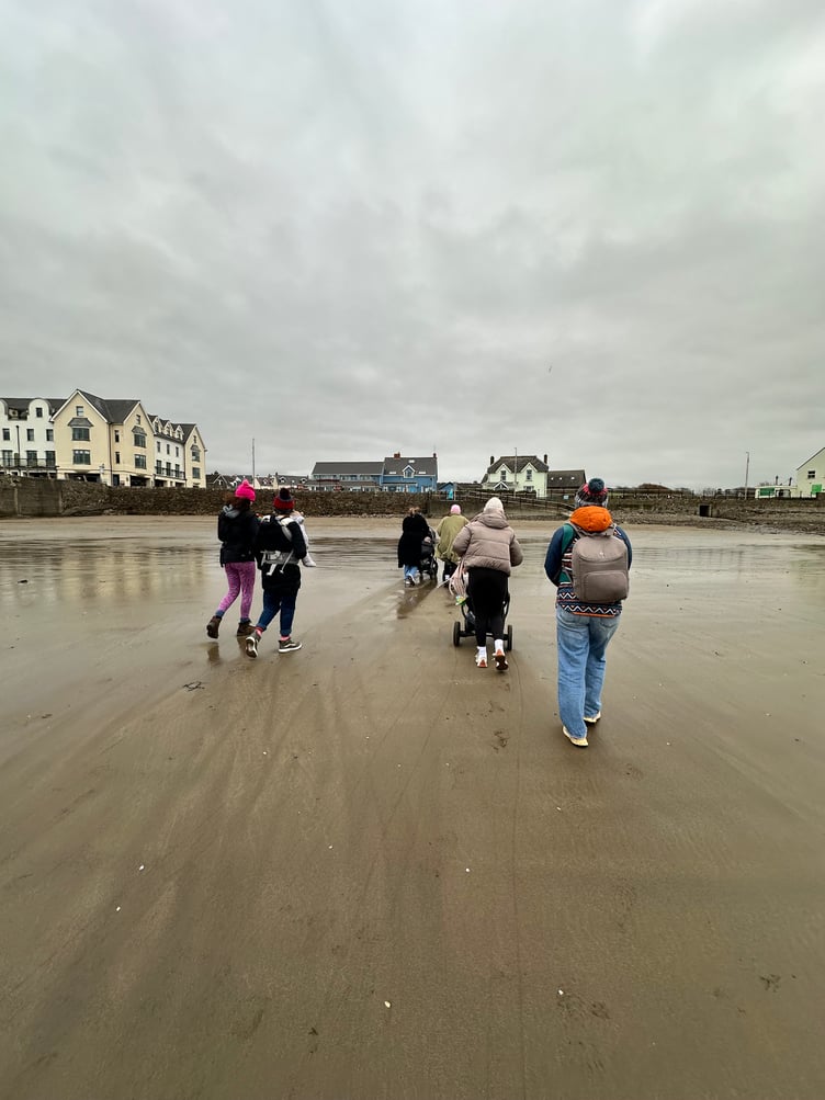 Parent and baby walking group strolling along Broad Haven beach in Pembrokeshire during a recent outing.
