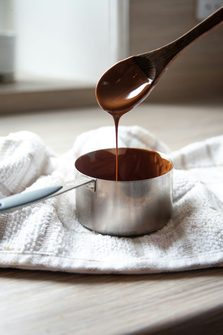 Melted chocolate dripping from spoon into saucepan