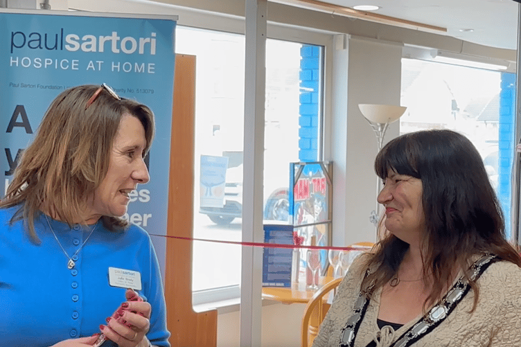 Paul Sartori Foundation’s Head of Retail Julia Brady hands the scissors to Pembroke Dock Mayor Michele Wiggins